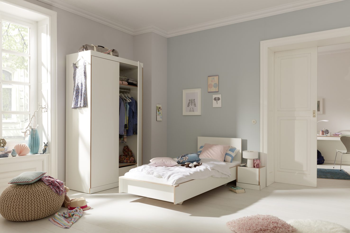 Helles Kinderzimmer mit weißem Flai Bett von Müller Möbelwerkstätten, 140 cm breit, und Kleiderschrank.
