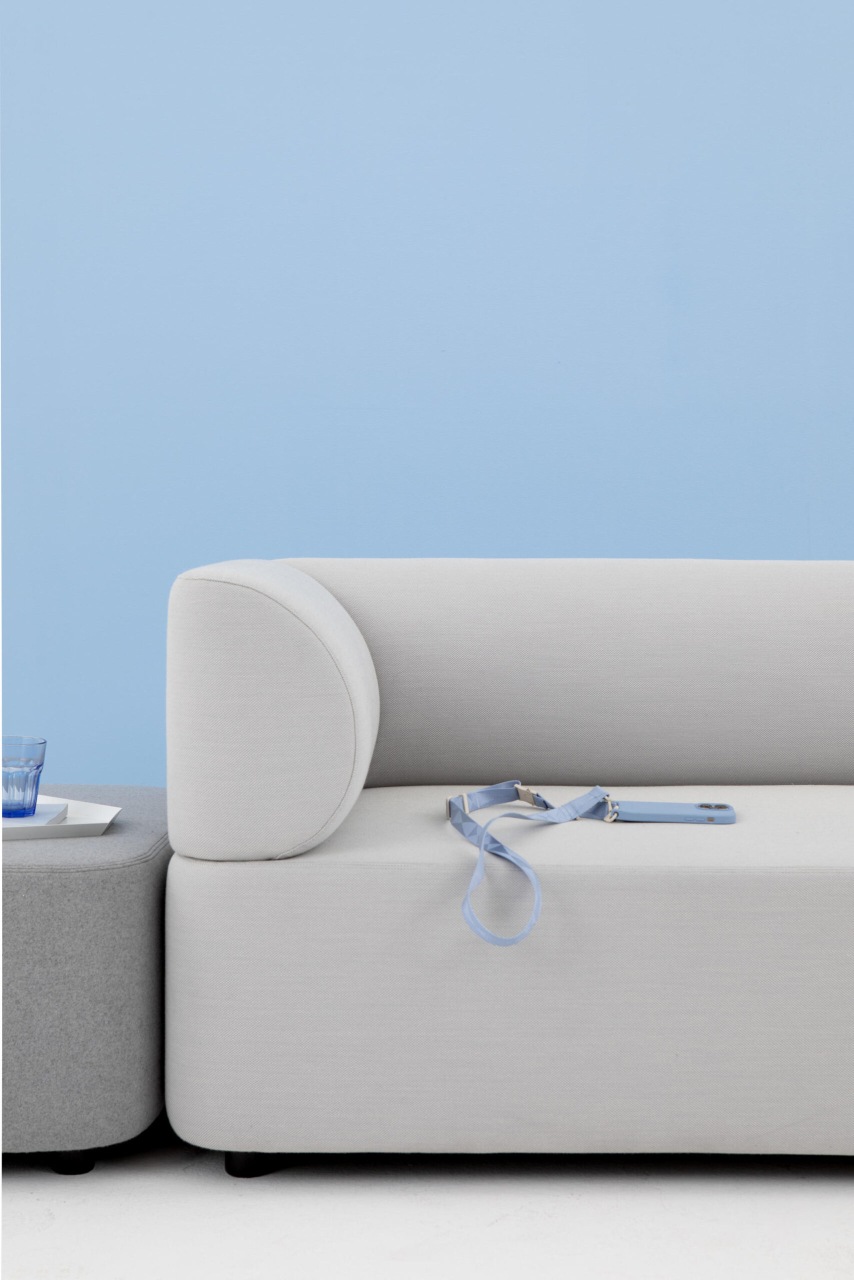 Helles Mezza Sofa Sitzelement von Cascando mit abgerundeter Armlehne und blauem Handyband.