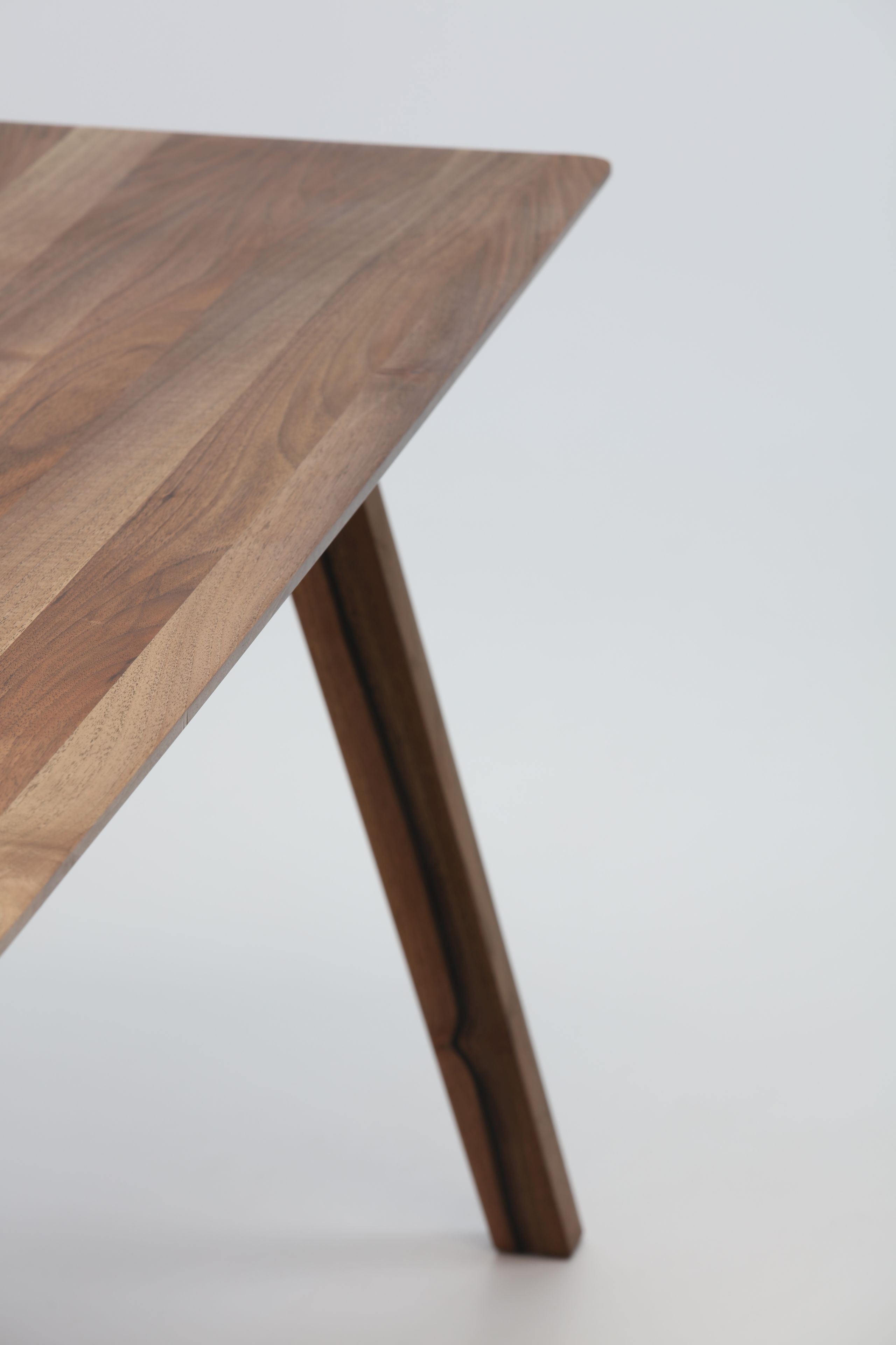 Detailaufnahme vom Monk Tisch von Prostoria, Tischplatte aus Nussbaumholz mit einem schrägen Tischbein.