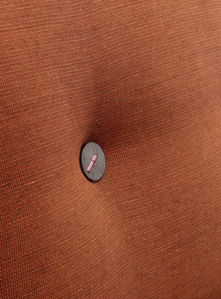 Detailaufnahme des braunen Vitra Polder Sofa Bezugsstoffes mit Knopf und pinkfarbenem Detail.