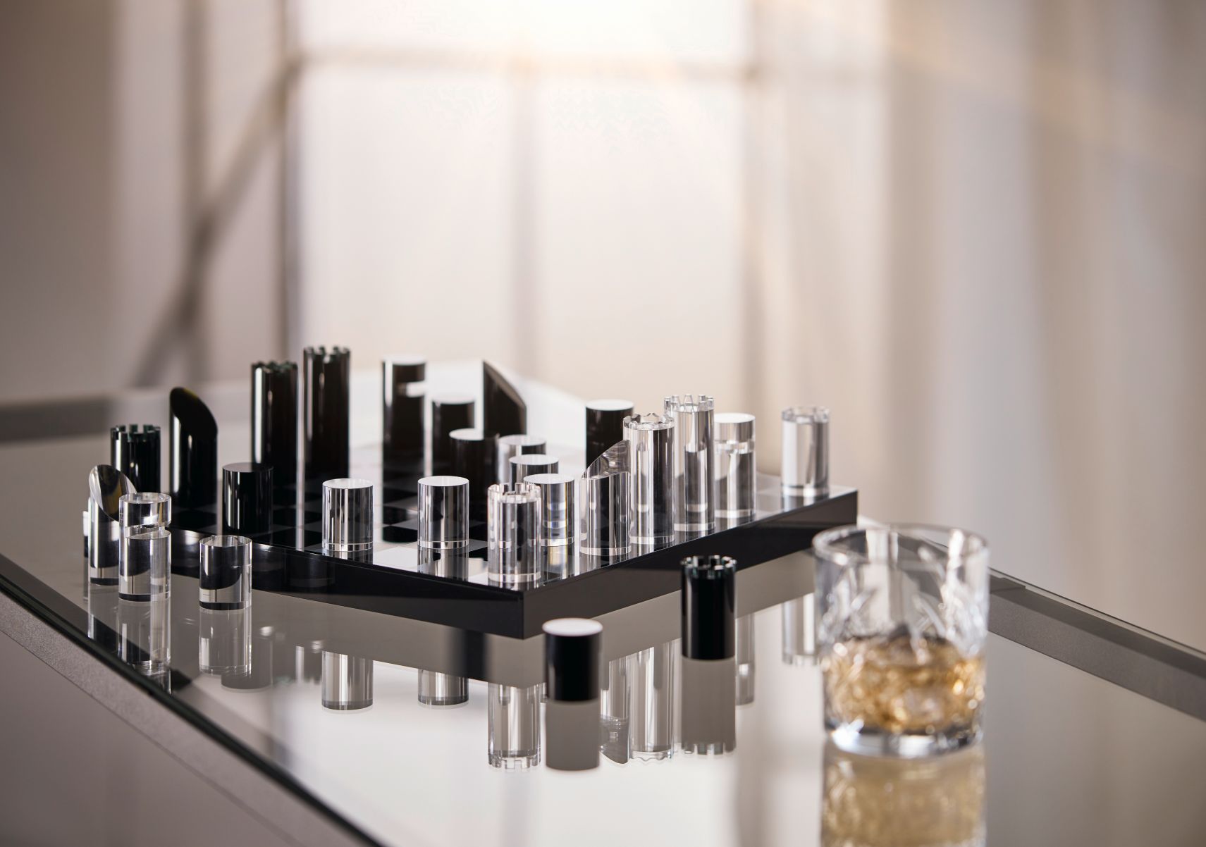 YAP Schachspiel von Philippi aus Acrylglas und poliertem Aluminium auf einem Tisch mit Whiskyglas.