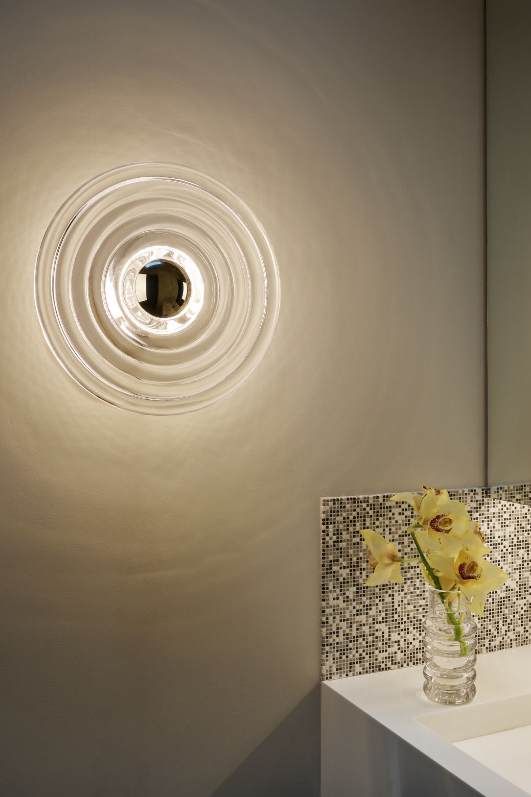 Press Surface Large Wandleuchte von Tom Dixon, moderne runde Glasleuchte an grauer Wand im Badezimmer.