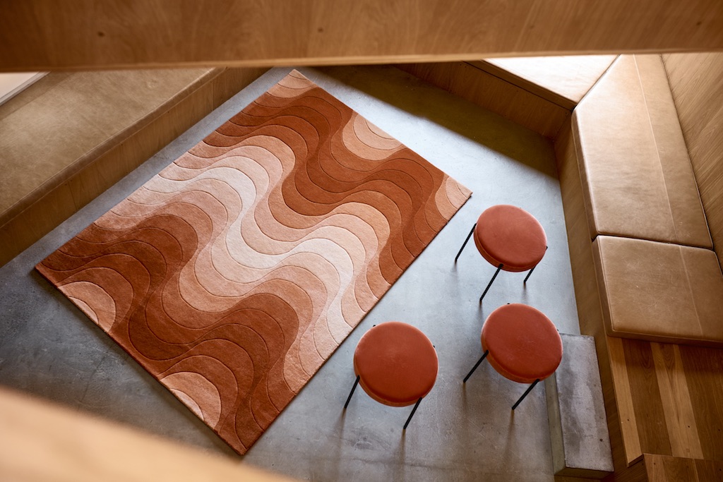 Drei orange Verpan Series 430 Hocker mit Teppich in modernem Wohnraum. Sitzmöbel und Einrichtung.