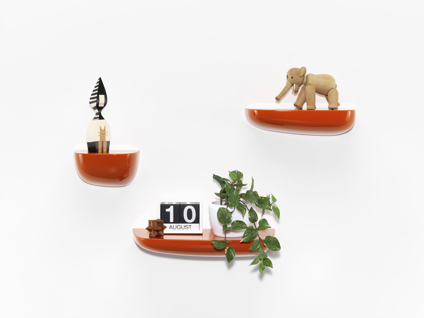 Orangefarbene Vitra Corniches Wandboards in verschiedenen Größen an einer weißen Wand mit Dekoration.