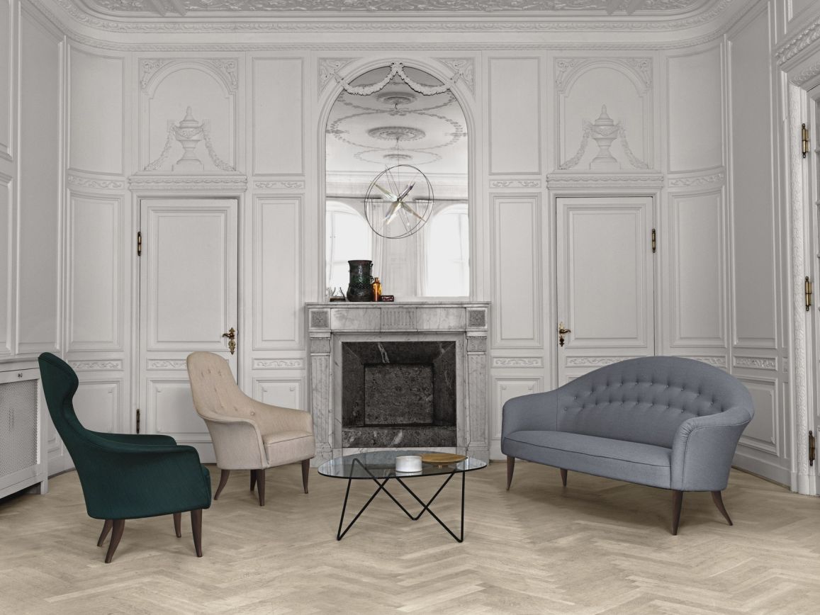 Eleganter Raum mit Gubi Couchtisch Pedrera, Sesseln und Sofa vor einem Marmorkamin.