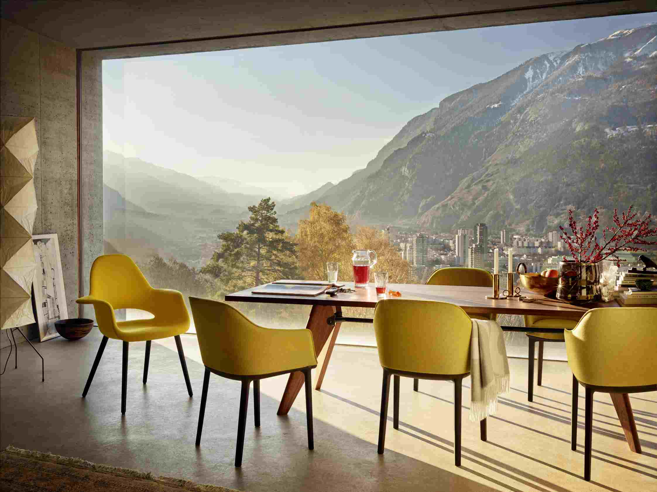 Table S.A.M Bois Tisch von Vitra mit gelben Stühlen in modernem Esszimmer mit Bergblick.