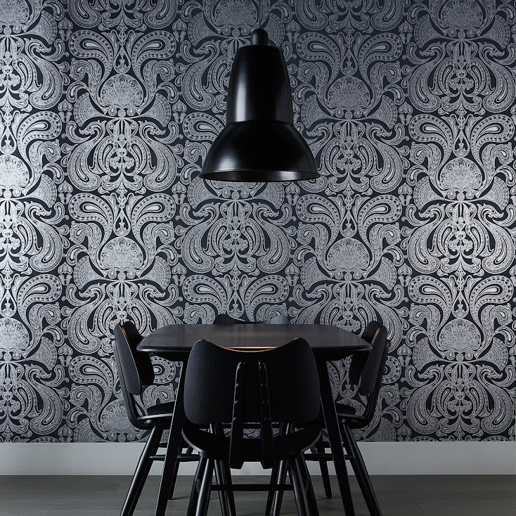Schwarze Anglepoise Original 1227 Giant Pendelleuchte über Esstisch mit Stühlen vor gemusterter Tapete.