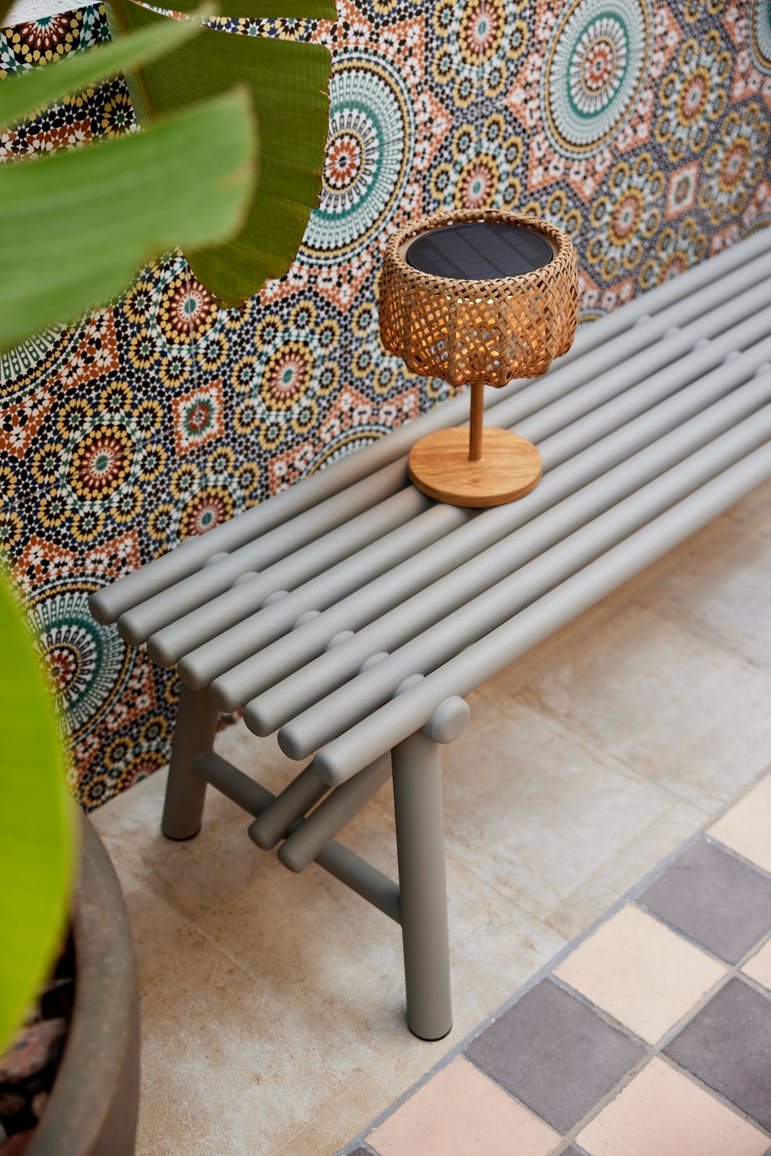 Kleine Cane-Line Illusion Glow Tischleuchte aus Rattan auf grauer Gartenbank. Outdoor-Beleuchtung für Terrasse.