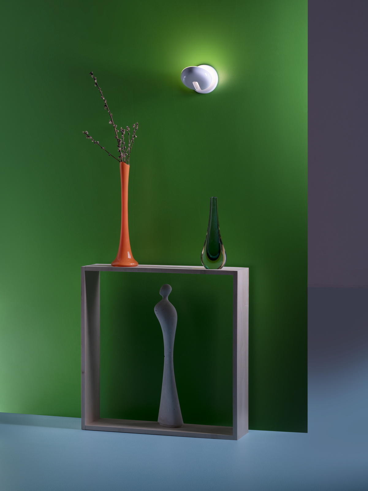 Cabriolette Wandleuchte von Martinelli Luce an grüner Wand, beleuchtet Arrangement mit Vasen und Skulptur.