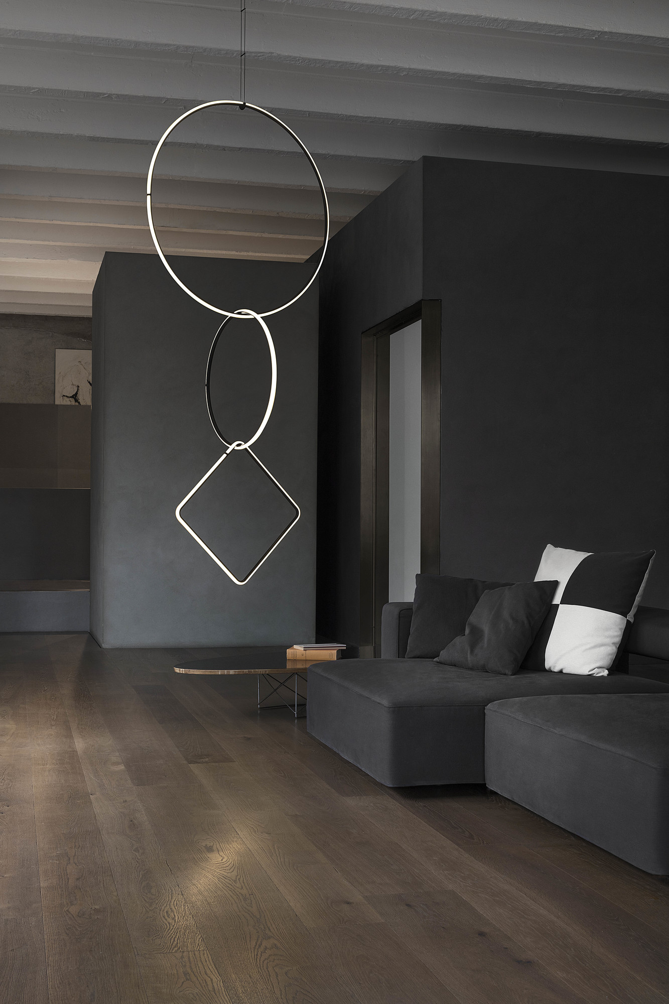 Flos Arrangements Pendelleuchte im modernen Wohnzimmer mit Sofa und Holzboden, minimalistisches Design.