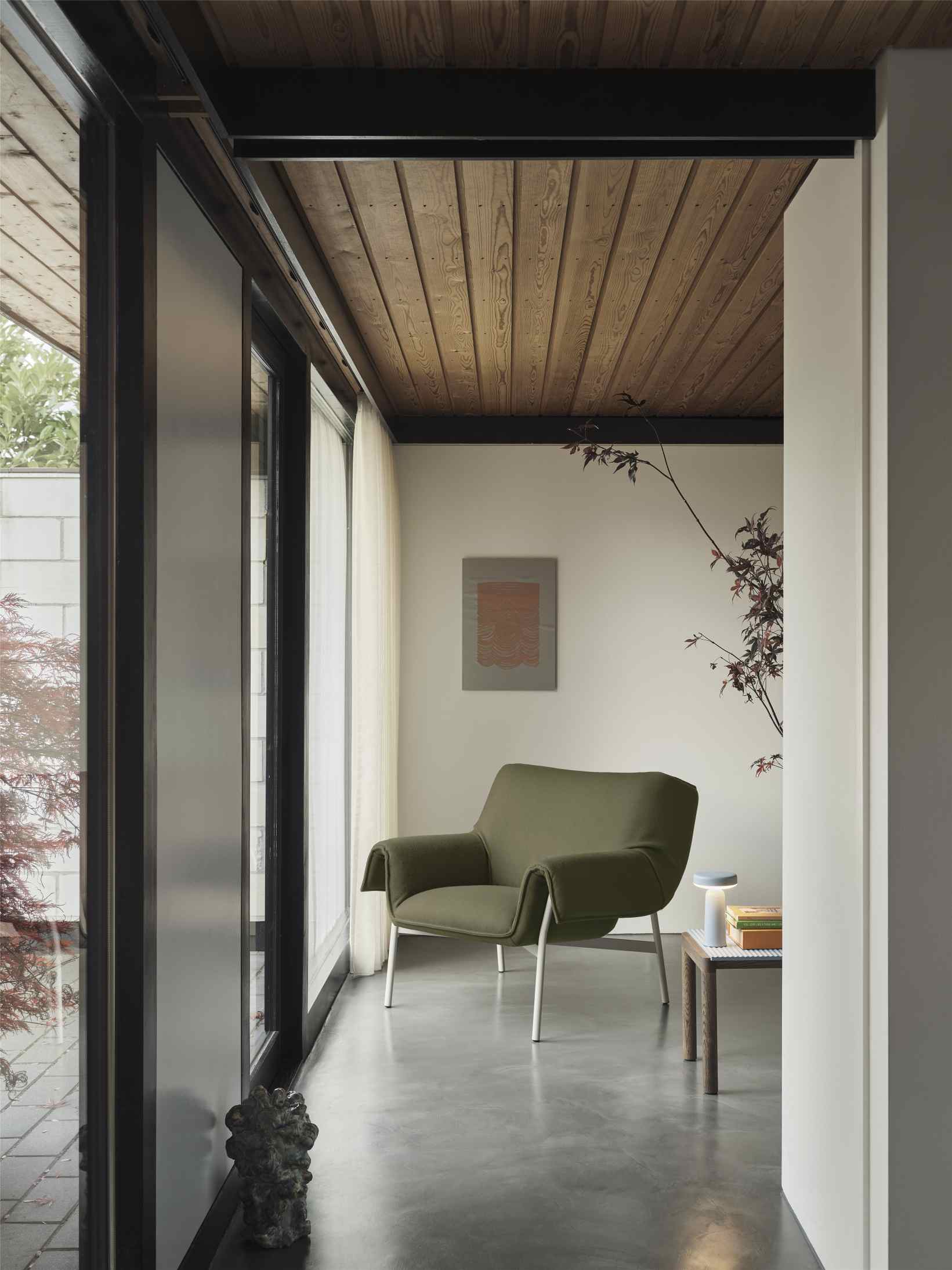 Moderner Wohnraum mit Muuto Sessel in Olivgrün und kleinem Beistelltisch, minimalistisches Design für Wohnzimmer.