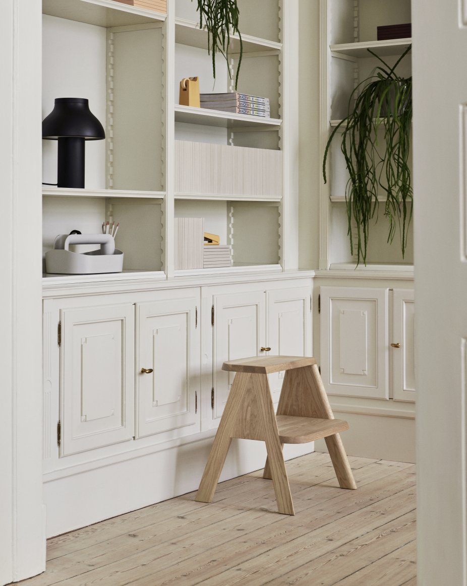 Heller Butler Hocker von Hay aus Eichenholz vor weißem Bücherregal auf Holzboden.