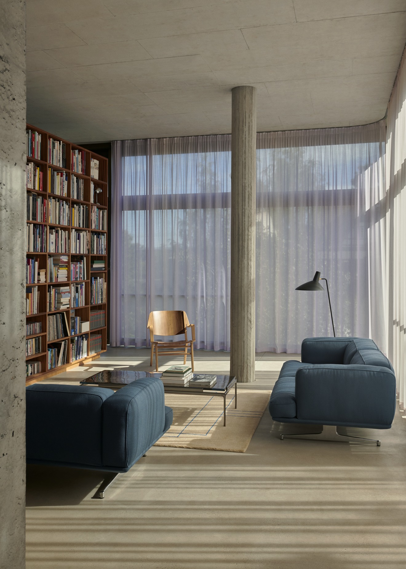 Wohnzimmer mit blauem Sofa und AndTradition Sett LN12 Couchtisch aus Glas und Stahl.