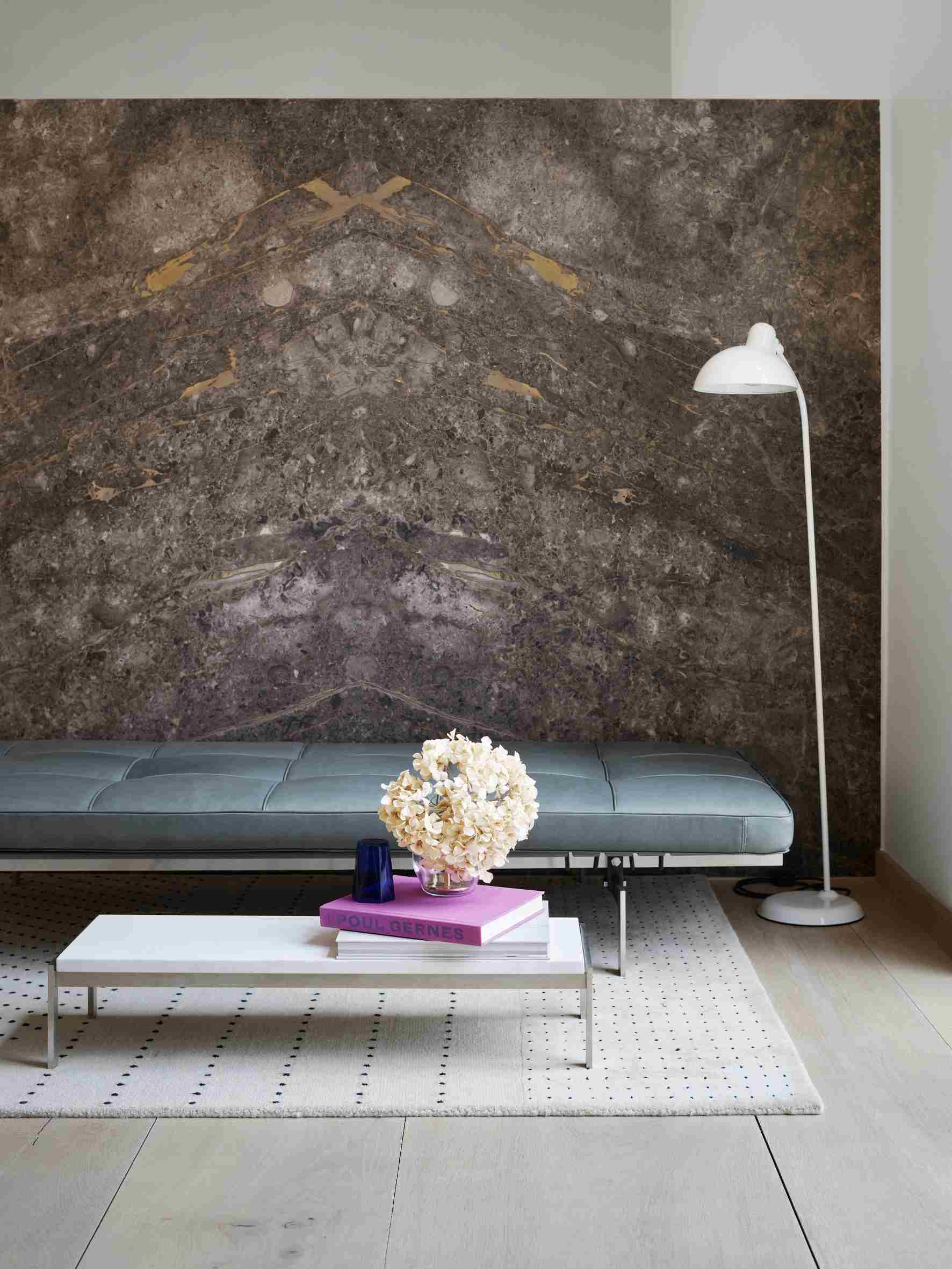 Helle Ledercouch PK 80 von Fritz Hansen im modernen Wohnzimmer mit Marmorwand und Stehlampe.