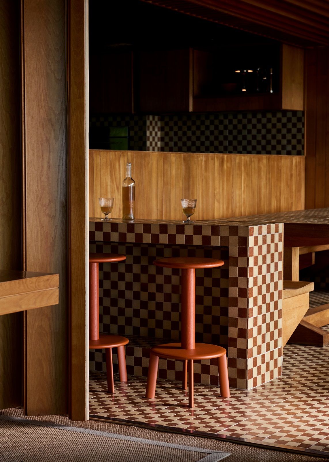Zwei Massif Hocker von AndTradition in einem Raum mit Schachbrettmuster. Design Hocker.