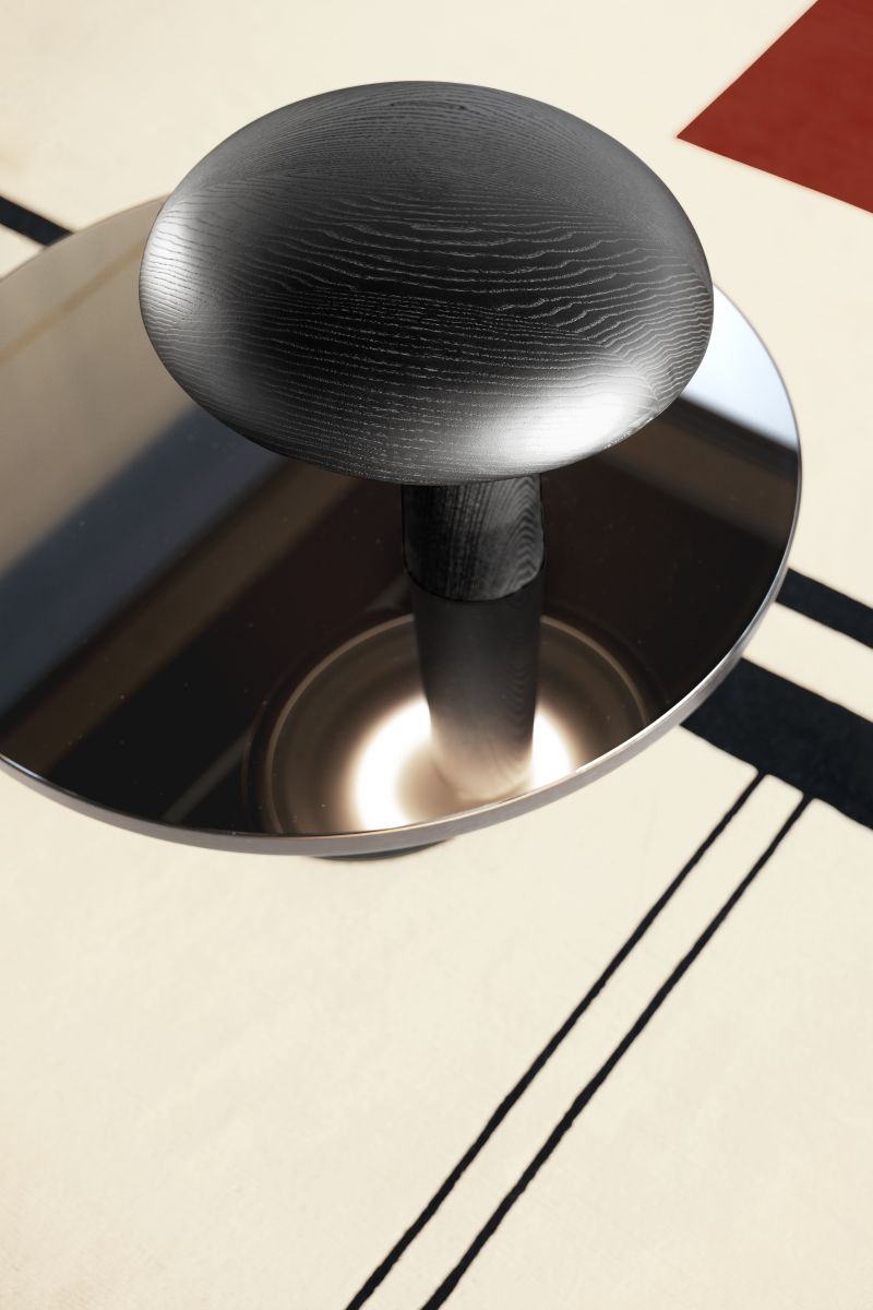 Nahaufnahme der ClassiCon Forma Tischleuchte mit schwarzem Holzschirm und reflektierendem Metallsockel auf gemustertem Teppich.