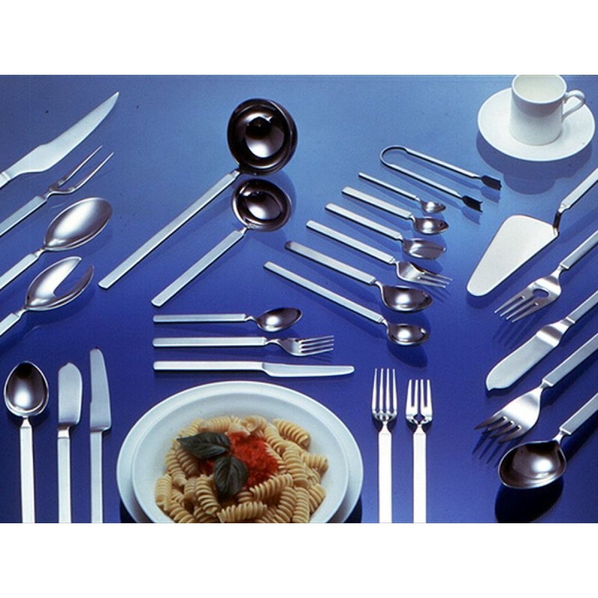 Alessi Dry Besteckgarnitur 30-teilig: Elegantes Edelstahl-Besteckset mit Suppenkelle, Saucenlöffel, Gabeln, Messer und Dessertlöffel auf blauem Hintergrund.