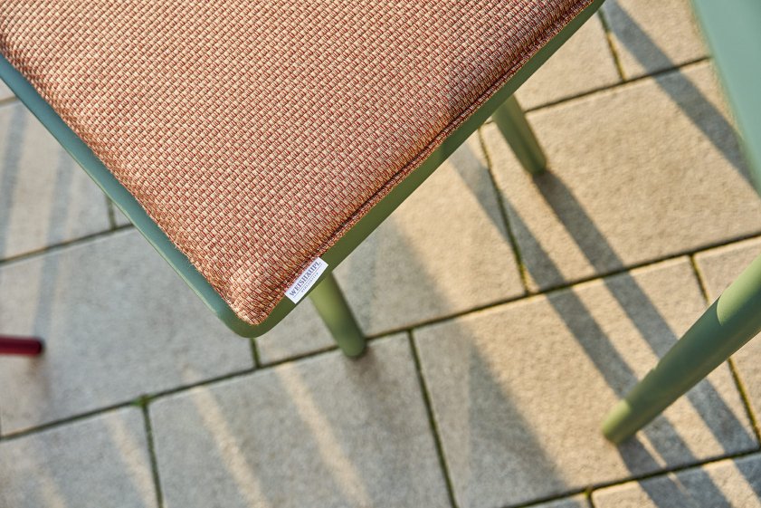 Detailaufnahme der Weishäupl Vapio Bank Outdoor Sitzfläche mit braunem Stoffbezug und grünem Gestell.