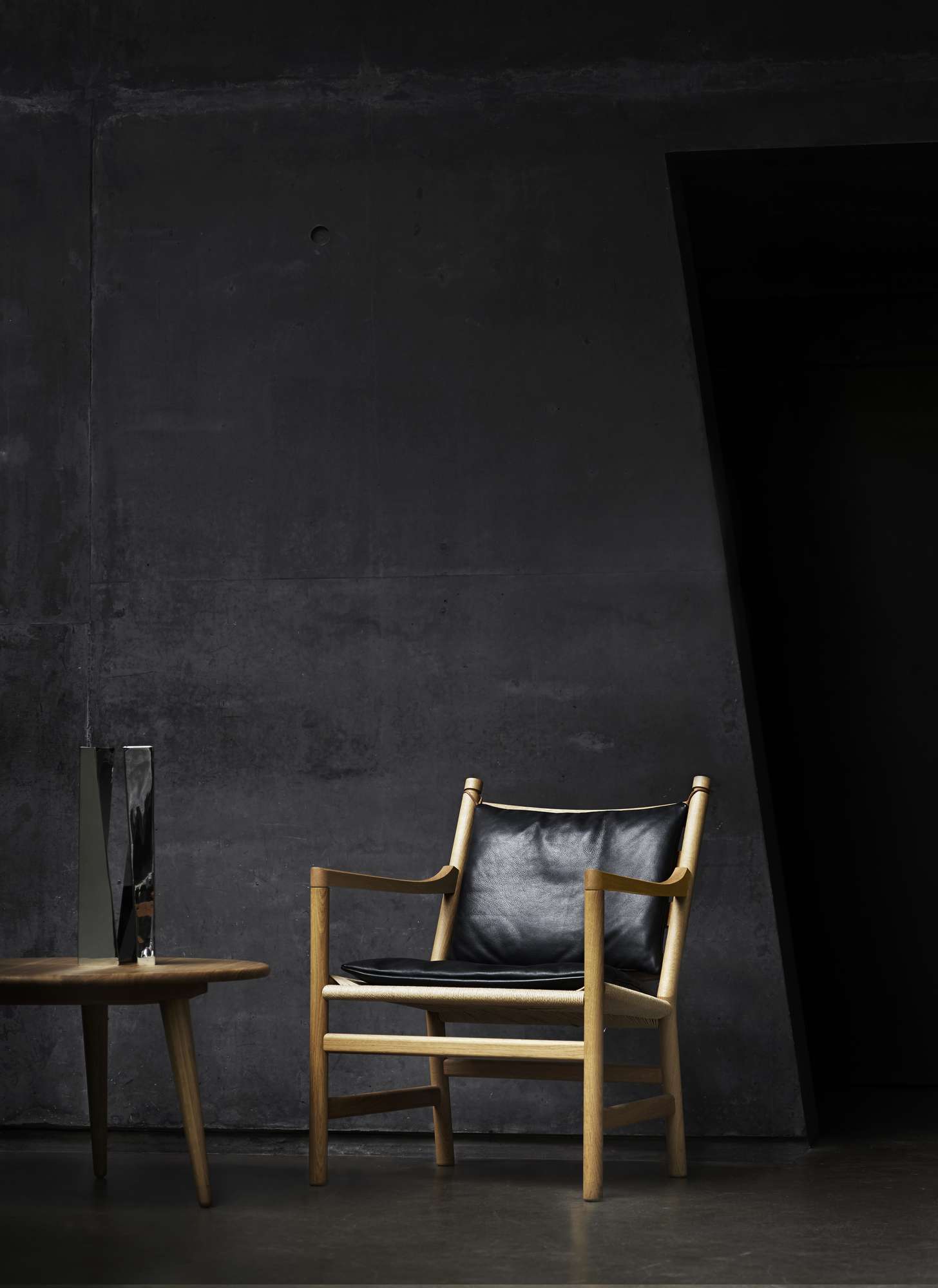 CH008 Couchtisch Eiche geölt von Carl Hansen & Søn neben Sessel mit Lederkissen.