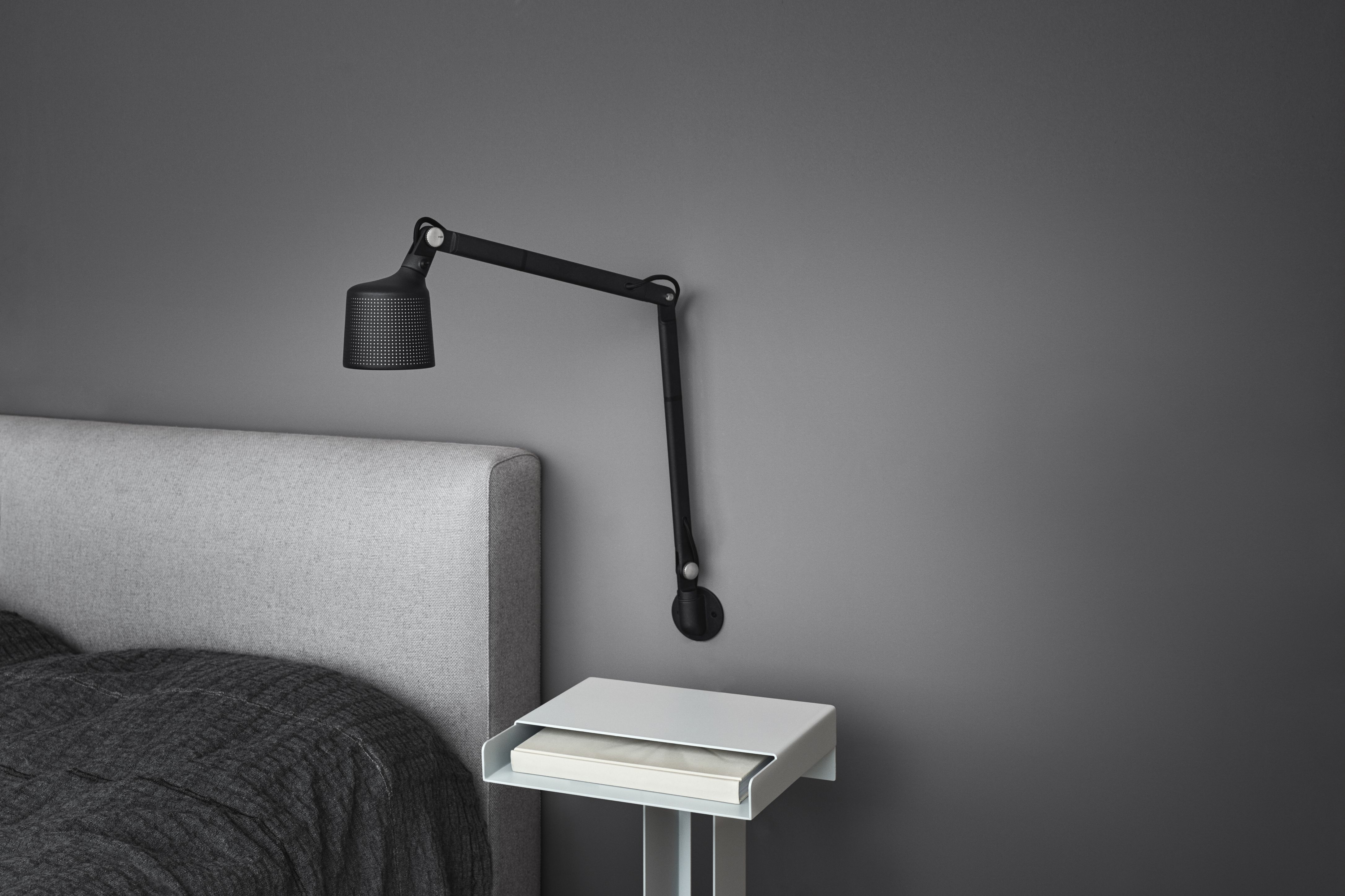Schwarze Vipp Wandlampe mit verstellbarem Arm über Nachttisch im Schlafzimmer. Moderne Innenarchitektur mit indirekter Beleuchtung.