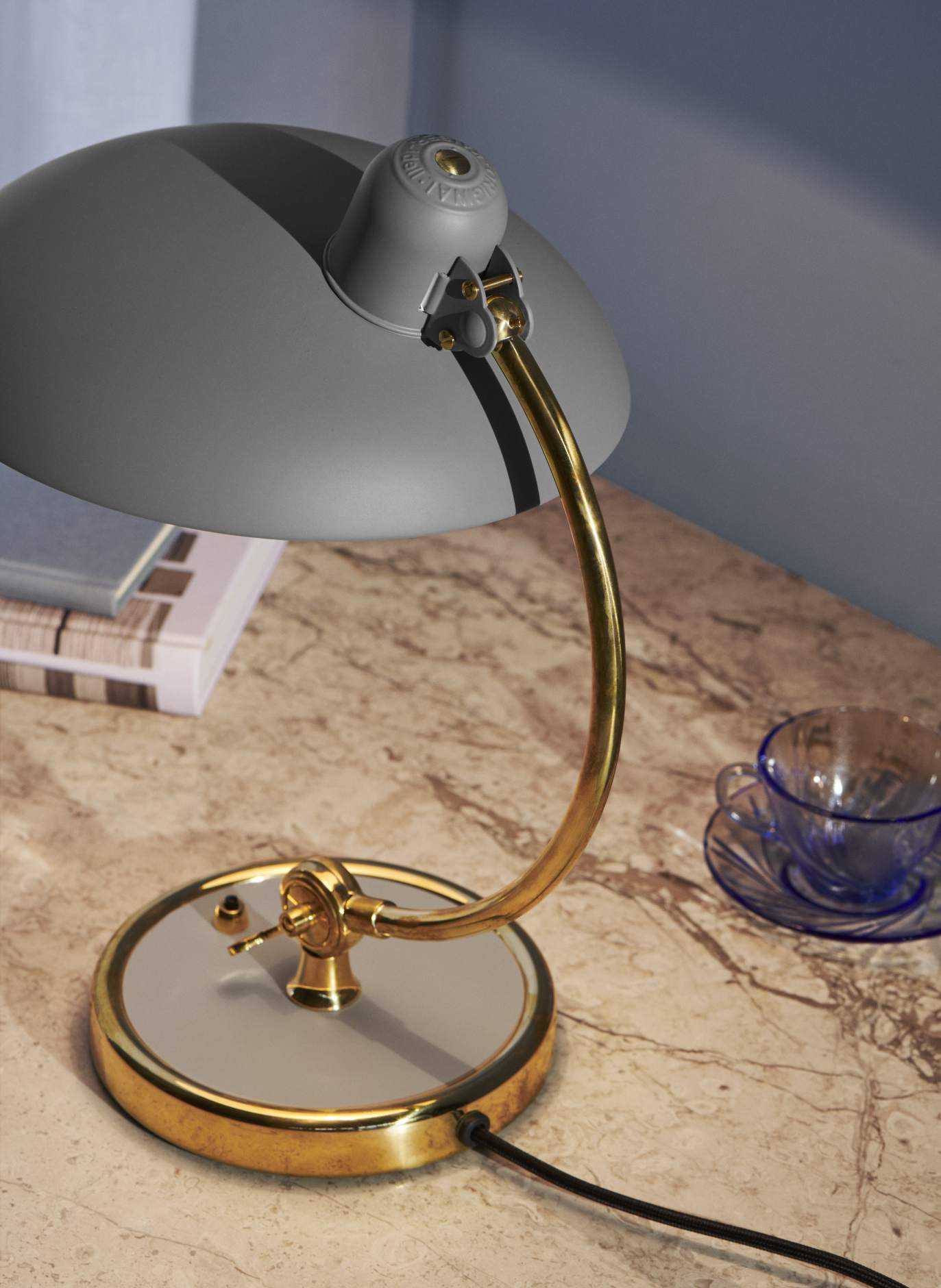 Nahaufnahme der grauen Kaiser Idell Tischleuchte von Fritz Hansen mit goldenem Gestell.