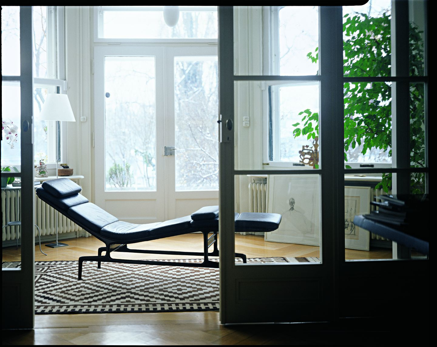 Schwarze Soft Pad Chaise Liege von Vitra im hellen Raum mit Teppich und Fensterfront.