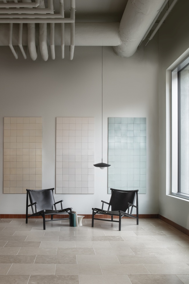Zwei schwarze Samurai Lounge Sessel von NORR11 in einem minimalistischen Interieur mit Fliesenkunst und Pendelleuchte.