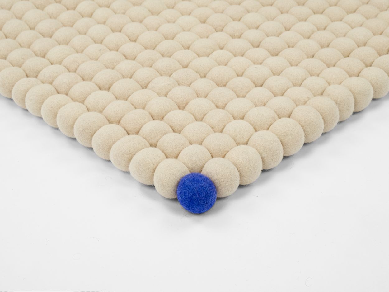 Beiger Filzteppich "Big One" von myfelt (140x200 cm) aus vielen Filzkugeln, eine blaue Kugel.
