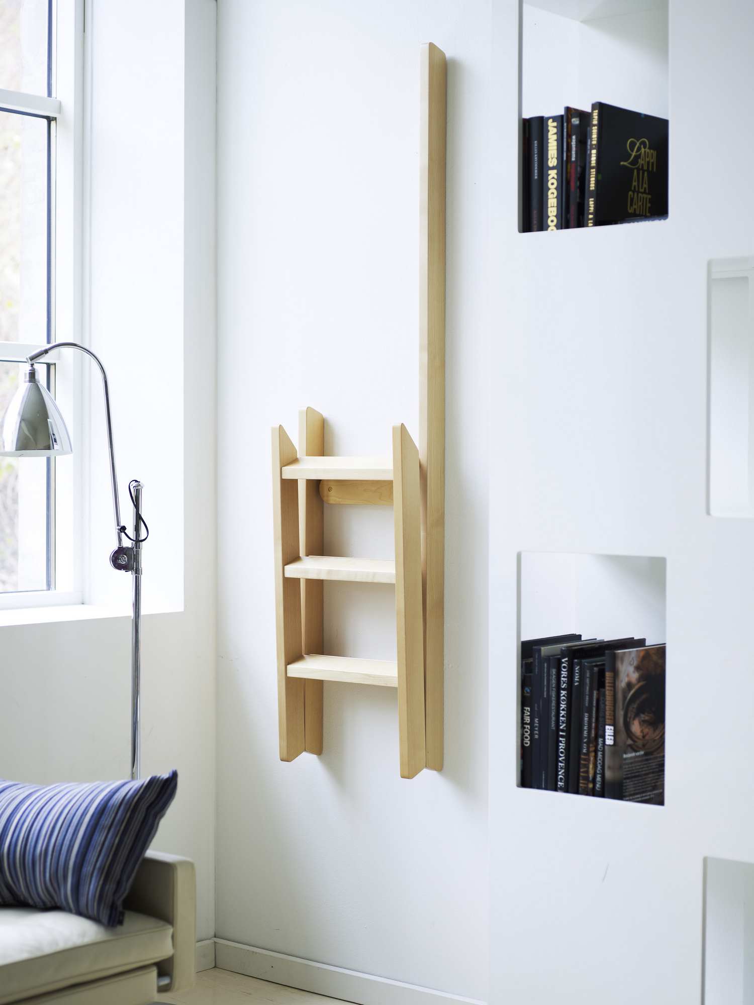 Hindevadgaard Trittleiter aus Holz, zusammengeklappt an einer weißen Wand, modernes Design für den Haushalt.