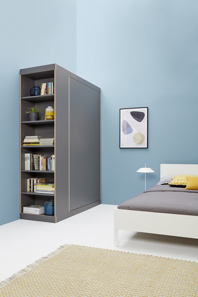 Helles Schlafzimmer mit weißem Nait Bett, grauem Schrank mit Regalen und gelbem Teppich für eine moderne Einrichtung.