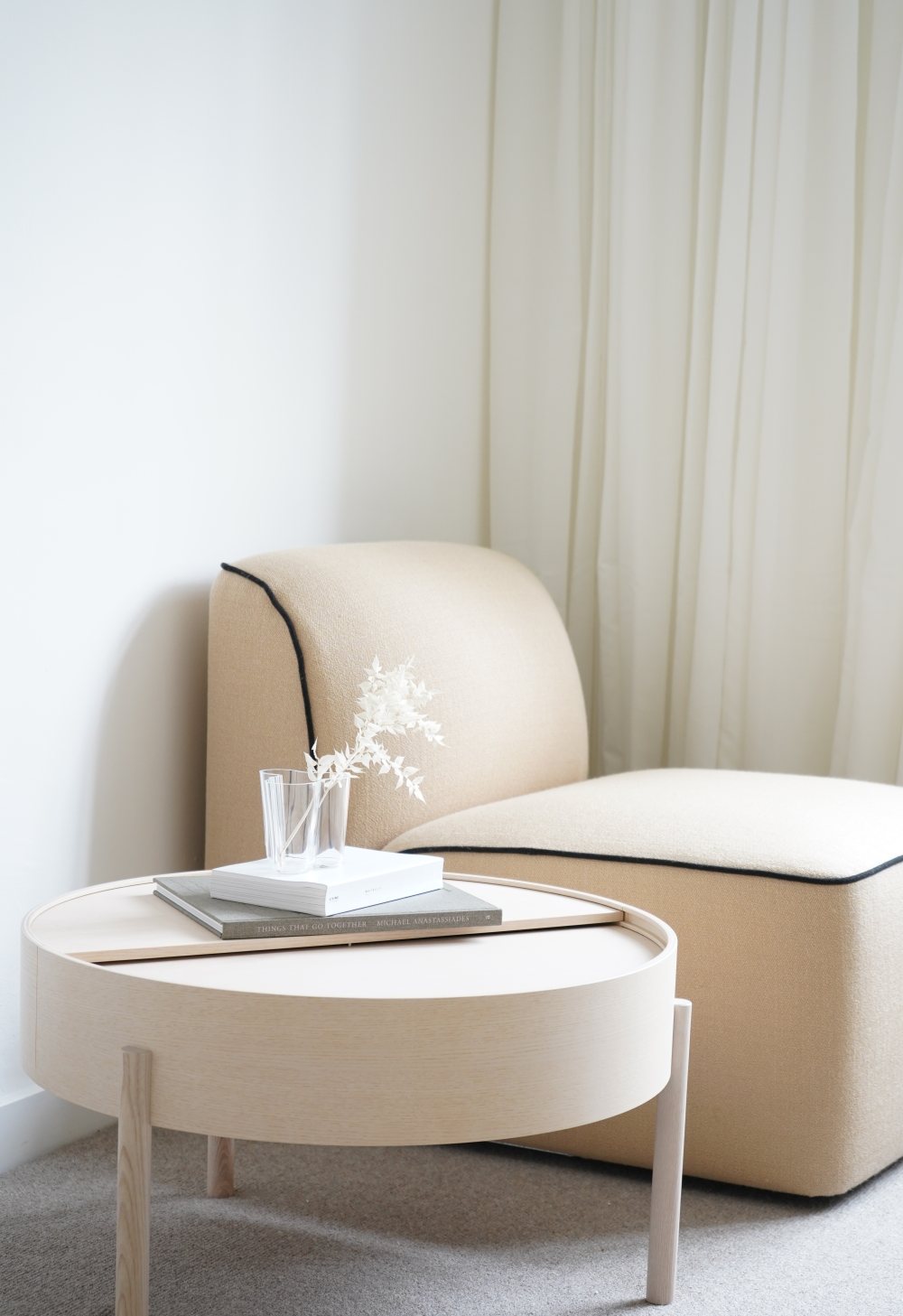 Arc Couchtisch Ø 66 cm von Woud in Esche weiß pigmentiert, mit Dekoration und Sessel.