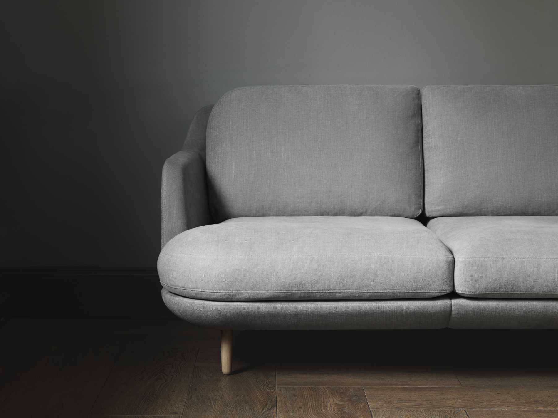 Graues Lune Sofa von Fritz Hansen, modernes 2-Sitzer Sofa mit hellen Holzfüßen auf dunklem Holzboden.