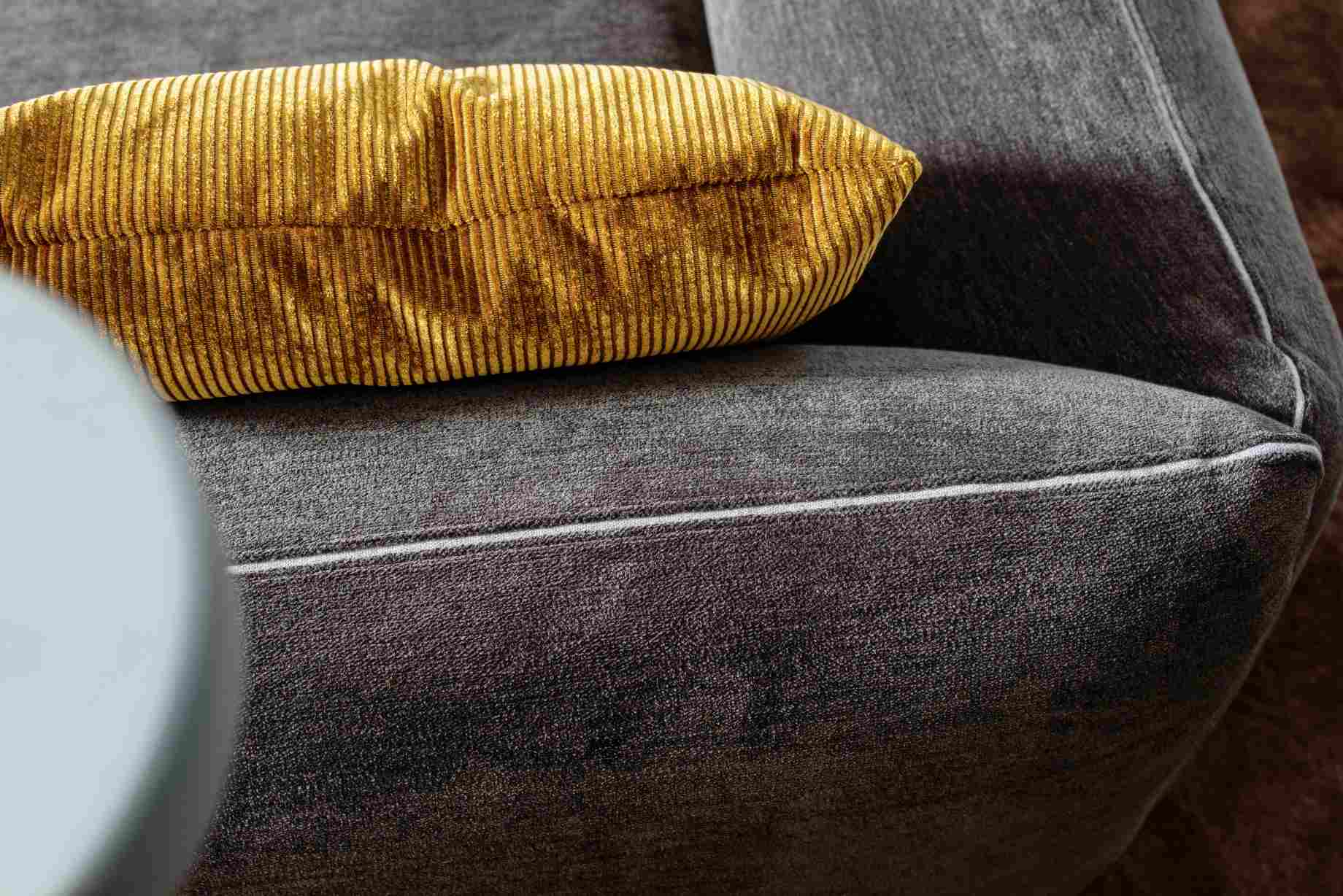 Nahaufnahme: Jalis21 Kissen in Goldcord auf grauer Couch, bequemes Rückenkissen für Wohnzimmer.