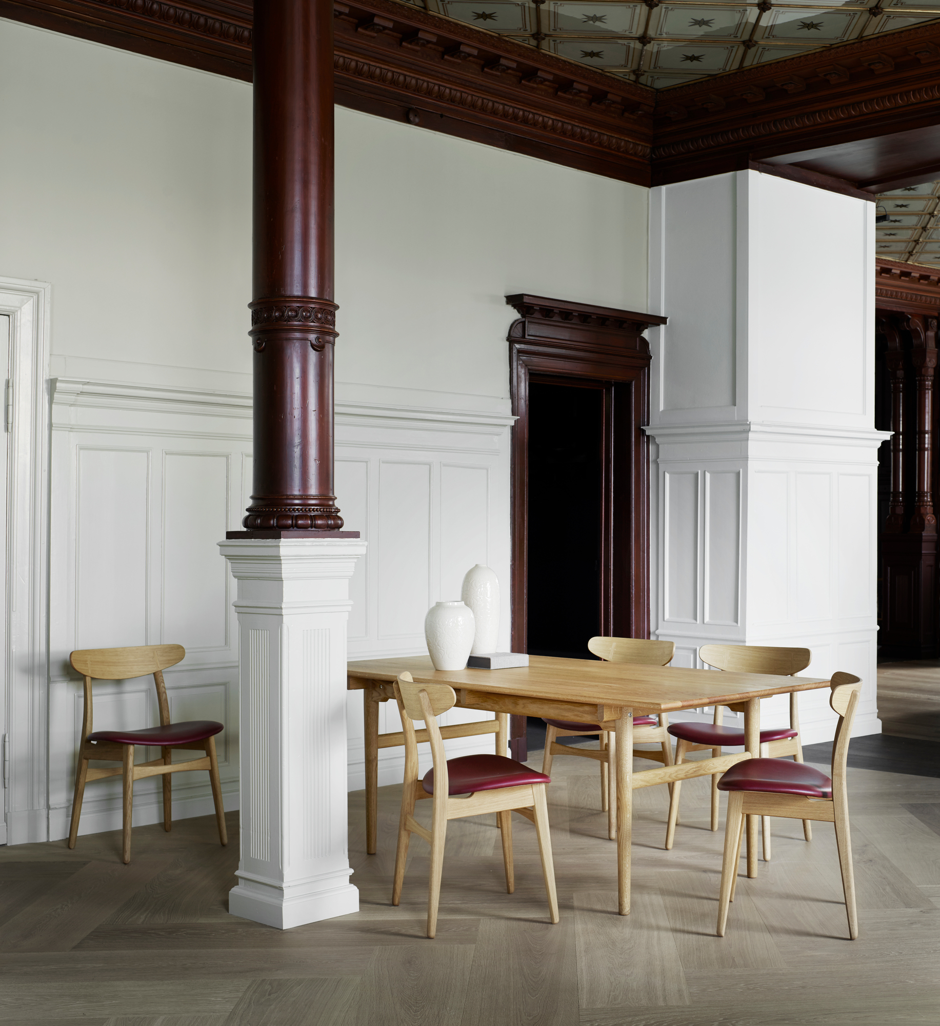 Esszimmer mit Holztisch und sechs CH30P Chair Stühlen von Carl Hansen mit roter Polsterung.