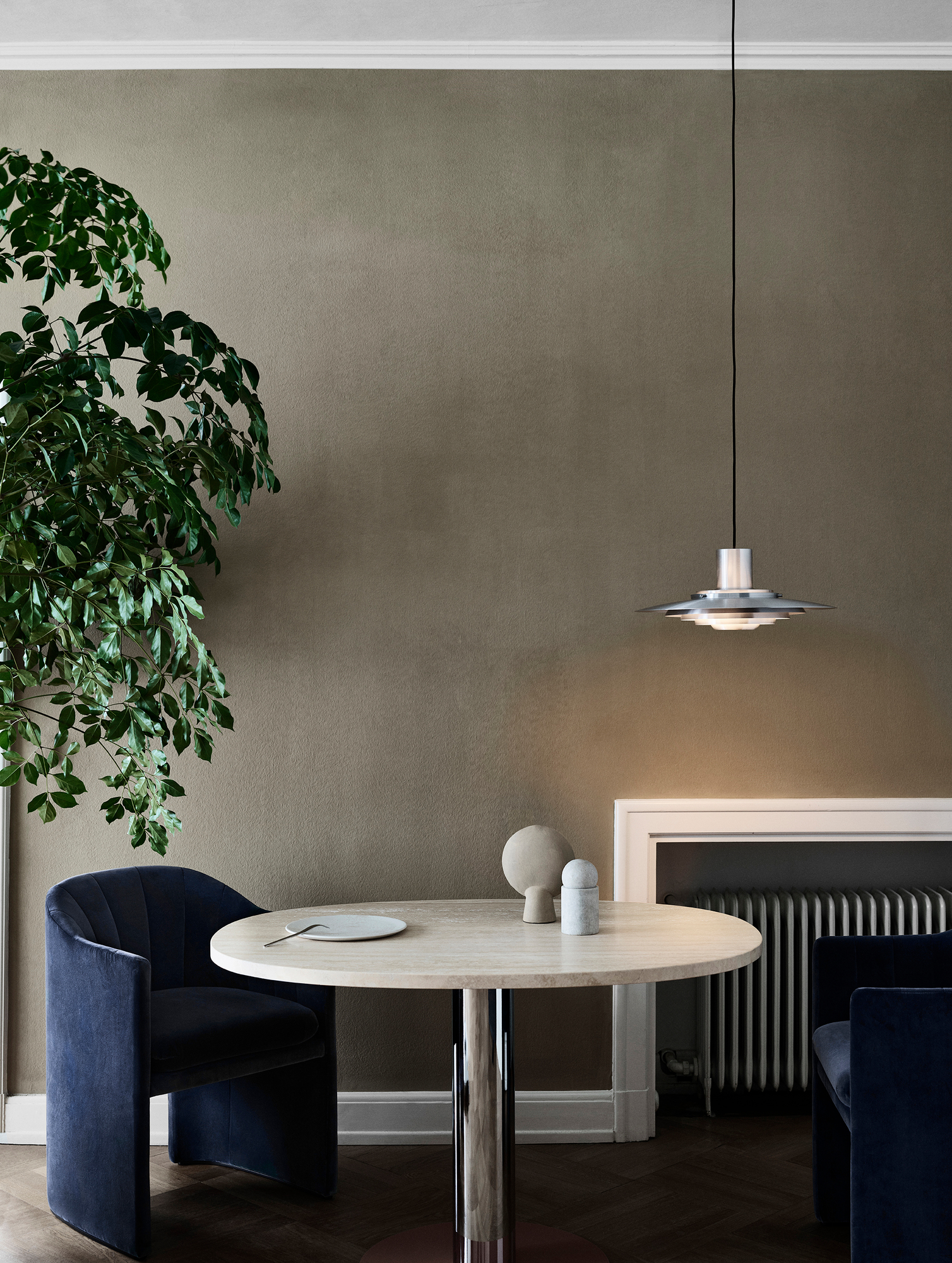 AndTradition P376 Pendelleuchte über Esstisch mit blauen Samtstühlen in stilvollem Interieur.