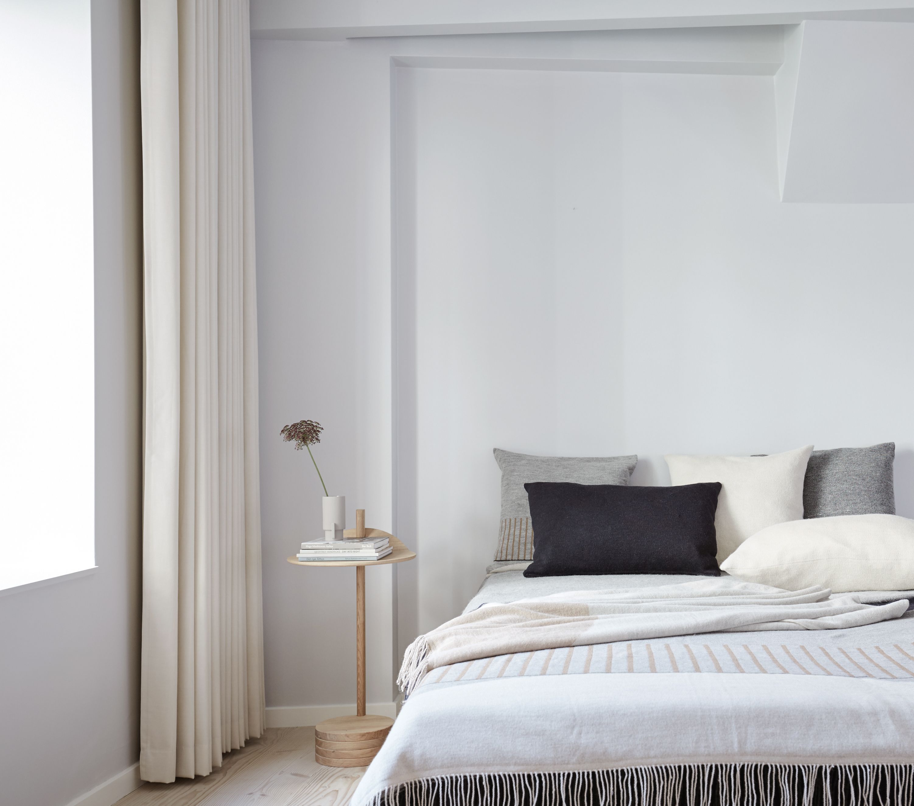 Helle Schlafzimmer-Szene mit Aymara Decke von Form & Refine, hellgrau mit Fransen und beigen Streifen.