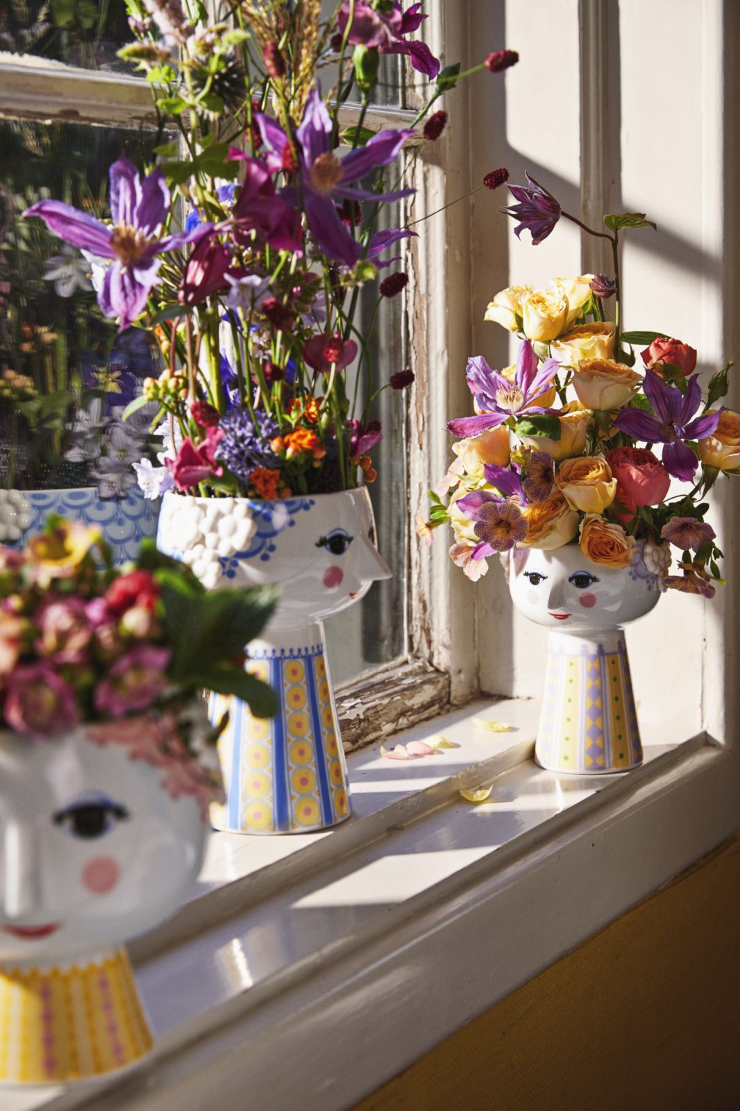 Drei Bjørn Wiinblad Eva Vasen mit Blumen auf einer Fensterbank, Lavendel-Farbtöne und dekoratives Design.