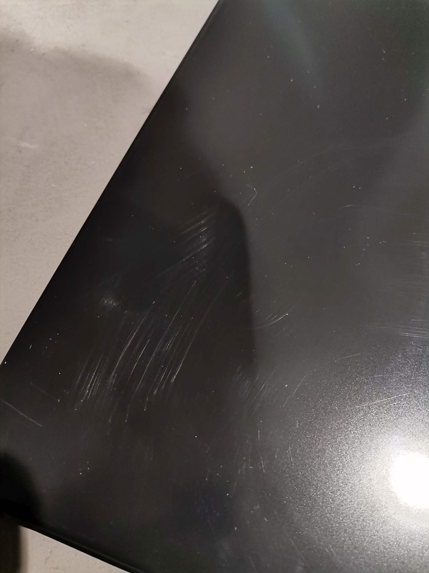 Detailaufnahme einer schwarzen USM Haller Tischplatte mit deutlichen Kratzern, Mängelexemplar.