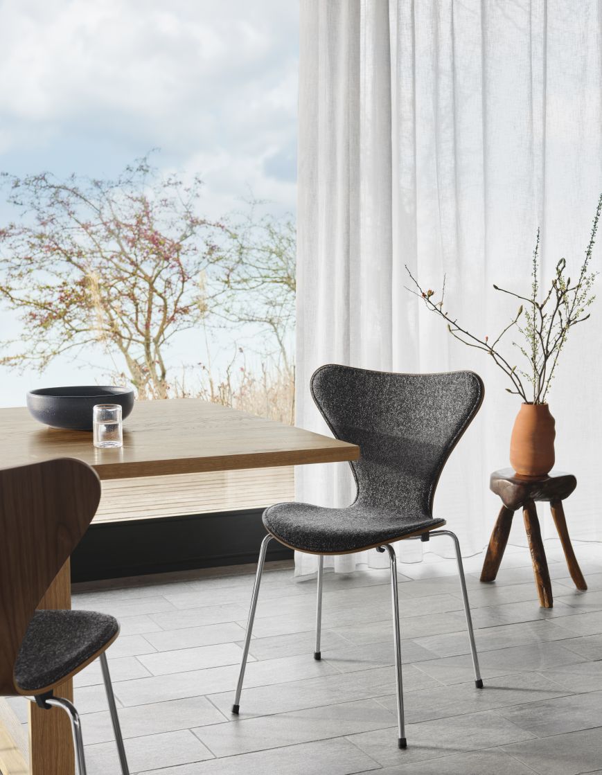 Grauer Siebener Stuhl von Fritz Hansen, Jubiläumsmodell, mit Stahlbeinen an einem Esstisch.