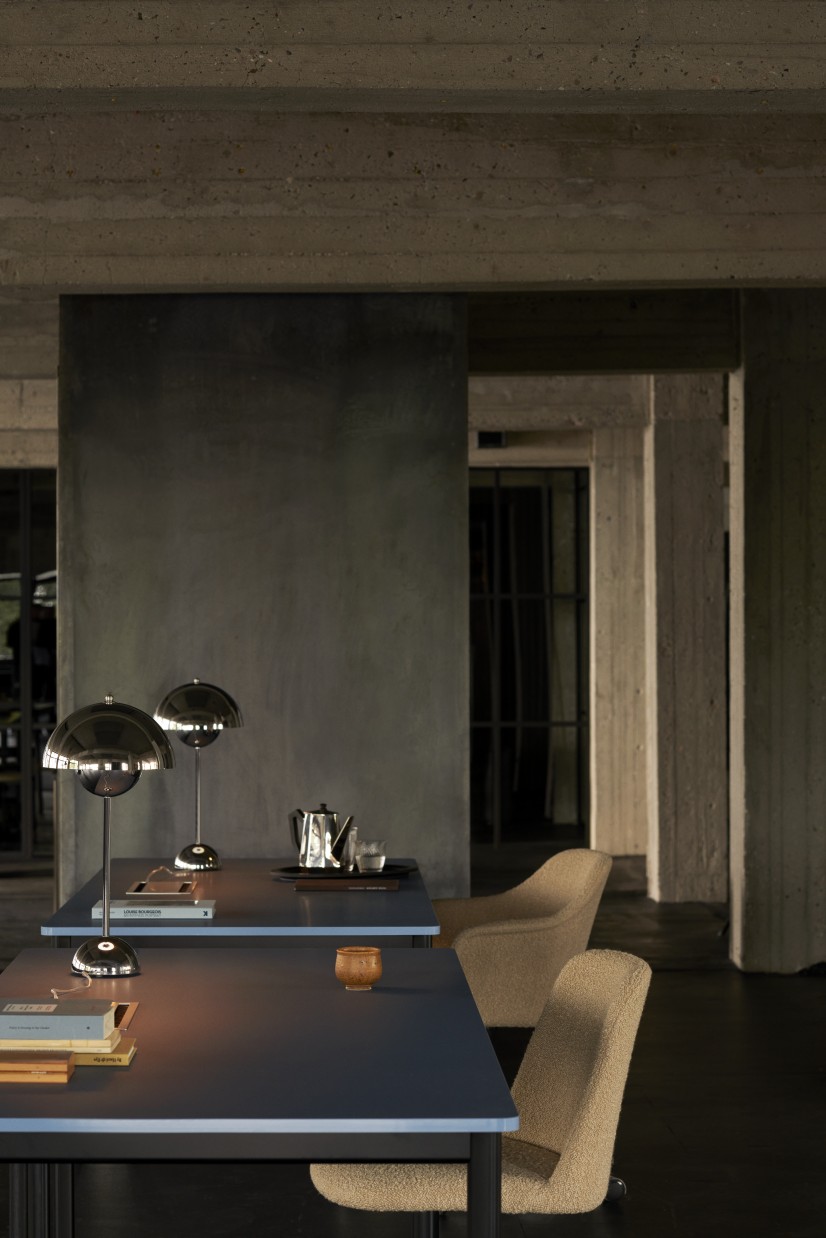 AndTradition Drip Table HW58 in dunklem Ambiente mit Design-Lampen und Stühlen. Moderner Esstisch für Wohnraum.