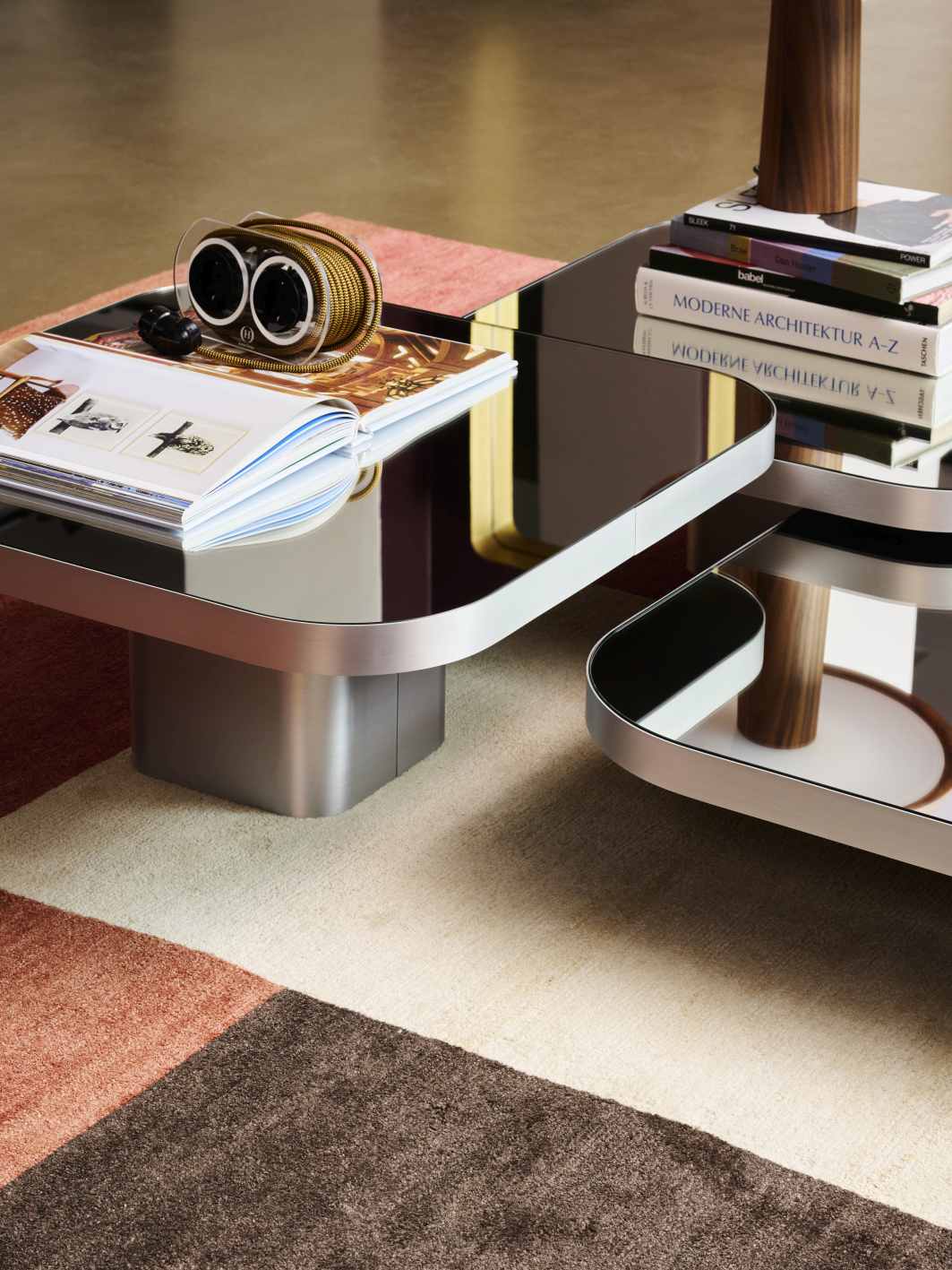 Bow Coffee Table von ClassiCon mit Glasplatte und Gegenständen auf einem modernen Teppich.