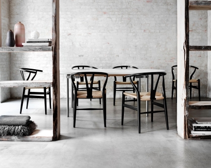 Esstisch mit schwarzen Wishbone Stühlen und heller Tischplatte im minimalistischen, modernen Esszimmer. Designermöbel für stilvolles Wohnen.