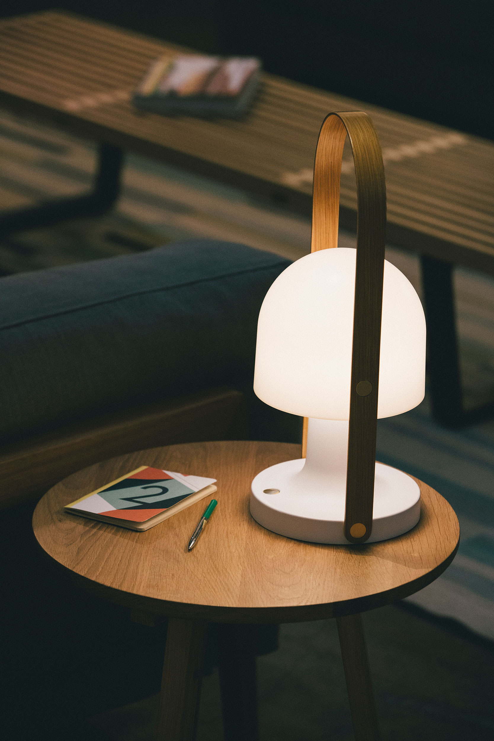 FollowMe Plus Akku Tischleuchte von Marset auf Holztisch, modernes Design mit Tragegriff.