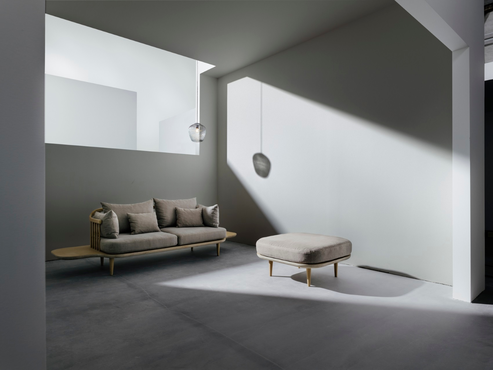 AndTradition Blown SW3 Pendelleuchte aus Glas über Sofa und Hocker in modernem Wohnraum.