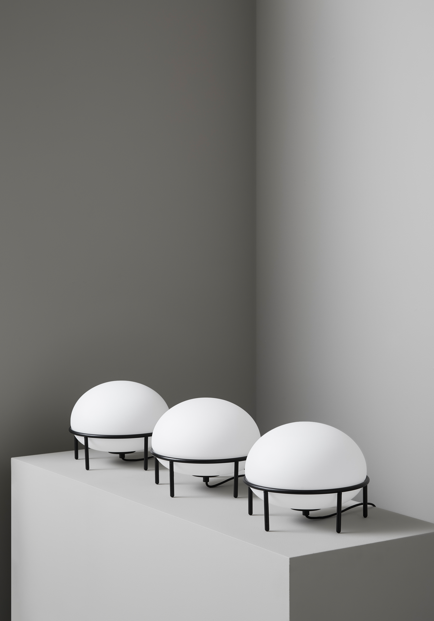Drei Woud Pump Table Lamp Tischleuchten mit runden, weißen Lampenschirmen und schwarzem Gestell.
