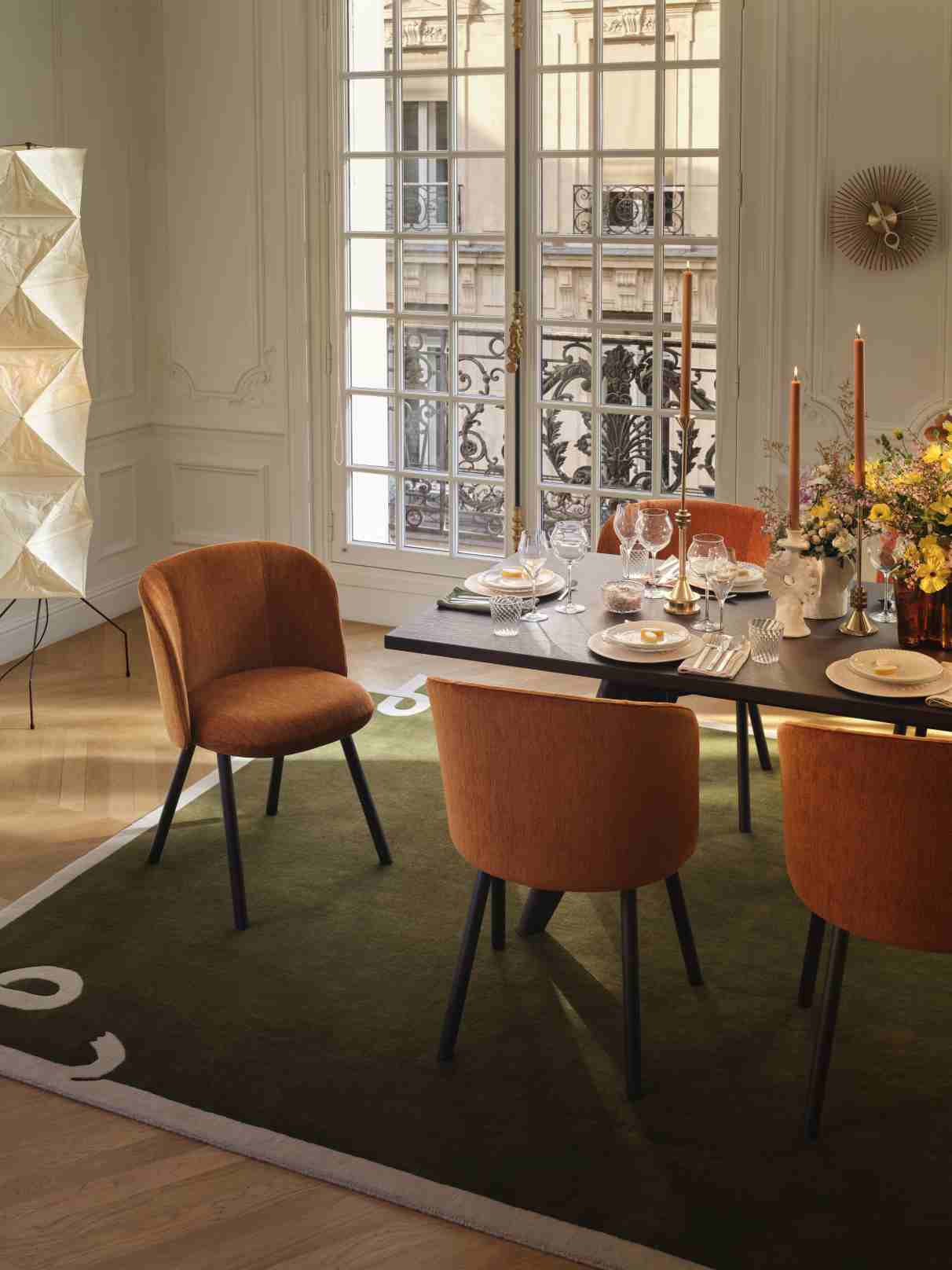 Esszimmer mit Vitra Stühlen in Orange und einer Popsicle Clock Wanduhr an der Wand.