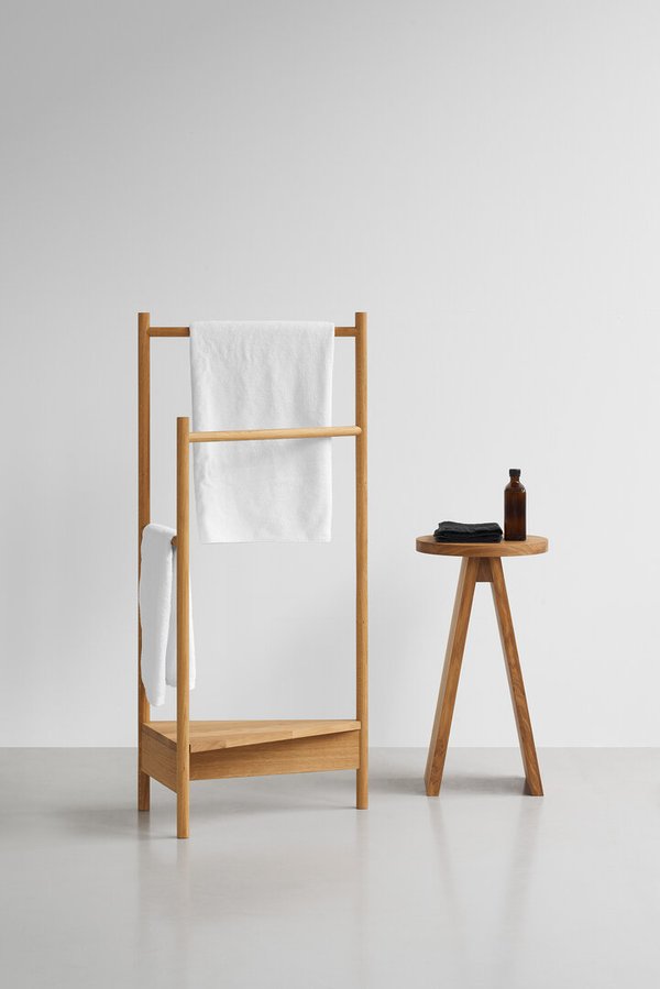 Heller Raum mit Handtuchständer aus Holz und e15 Hocker groß EK02 mit Handtüchern und Flasche.