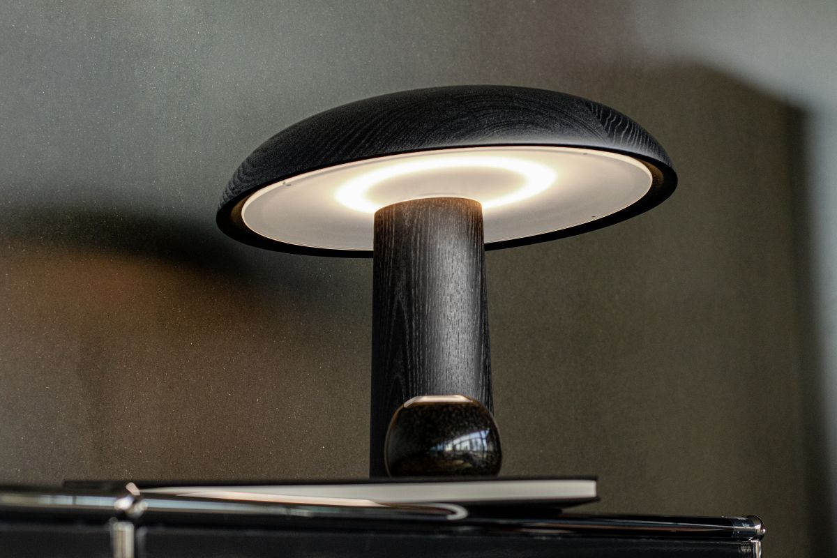 Forma Tischleuchte von ClassiCon aus dunklem Holz mit sanftem, indirektem Lichtschein.