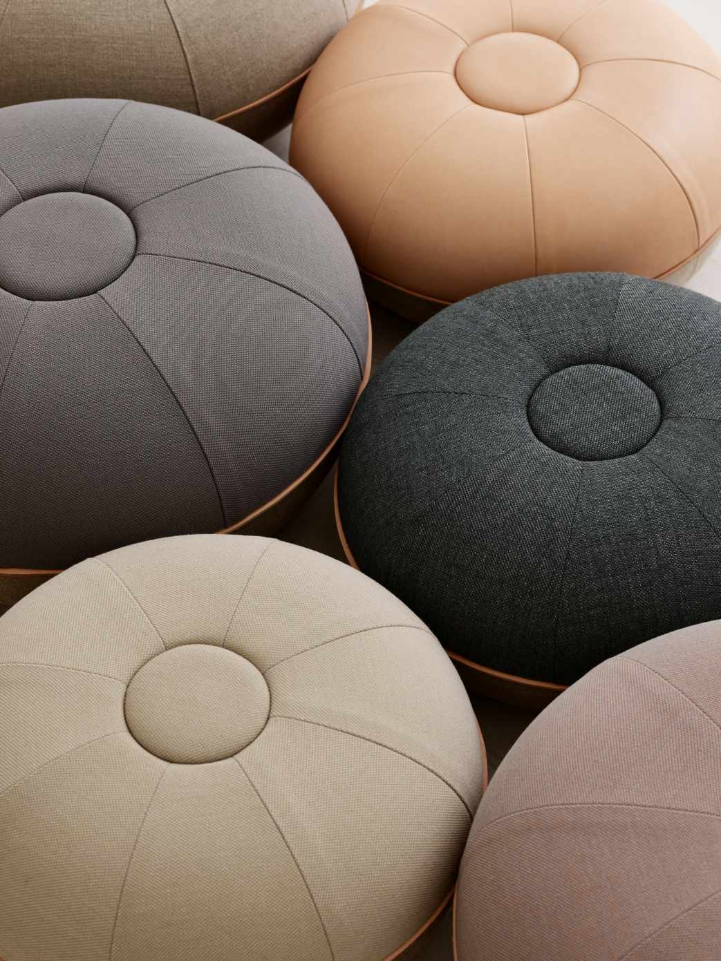 Nahaufnahme verschiedenfarbiger Fritz Hansen Pouf Small Hocker aus Stoff und Leder.