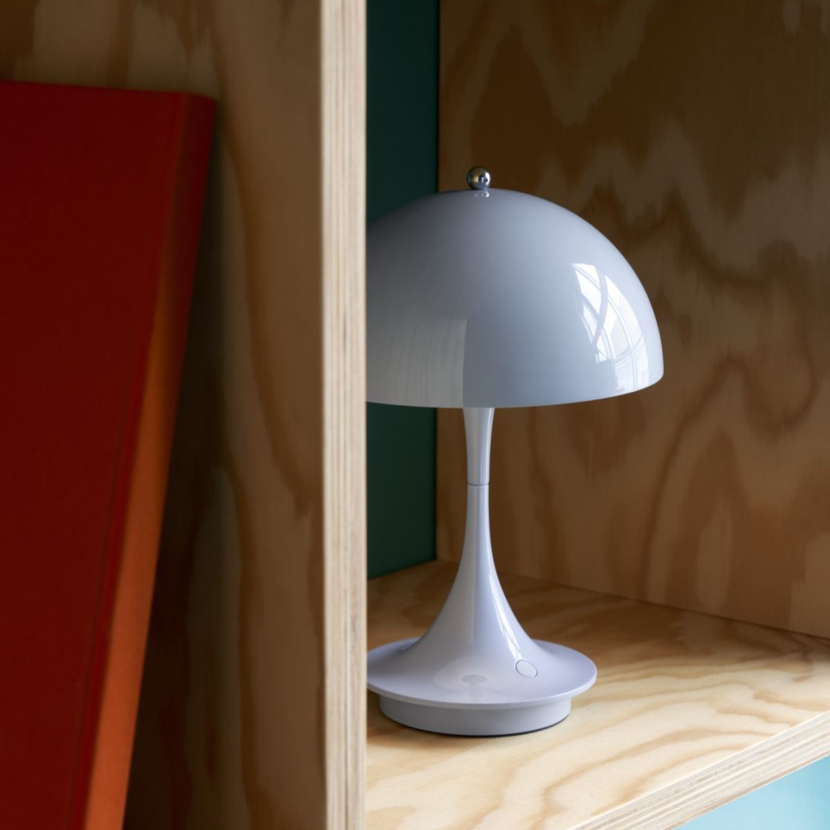 Nahaufnahme einer modernen, grauen Tischleuchte im Pilzdesign auf einem Holzregal. Dekorative Beleuchtung für Wohnzimmer und Schlafzimmer.